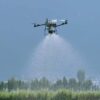 Dron agrícola DJI Agras T70P en pleno vuelo pulverizando un cultivo en campo abierto.