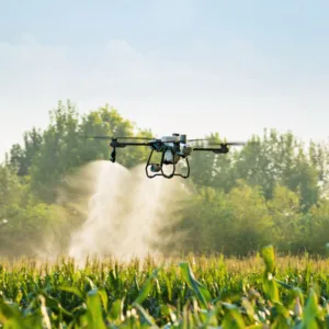 Dron agrícola DJI Agras T50 en pleno vuelo de pulverización sobre campo de cultivo