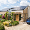 Coche eléctrico conectado a un cargador inteligente en una vivienda con paneles solares en el tejado, aprovechando la energía solar.