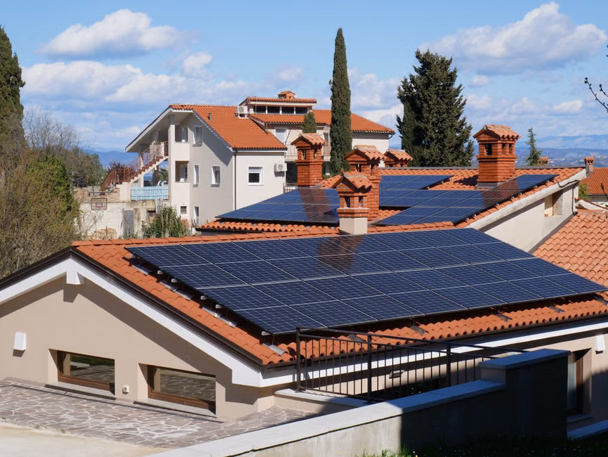 Fotografía de detalle de una instalación fotovoltaica en un tejado residencial, mostrando los rieles y la estructura metálica que sujetan los paneles solares.